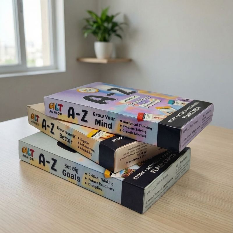 Stack of 'A-Z' educational card game boxes on a table with a plant in the background.